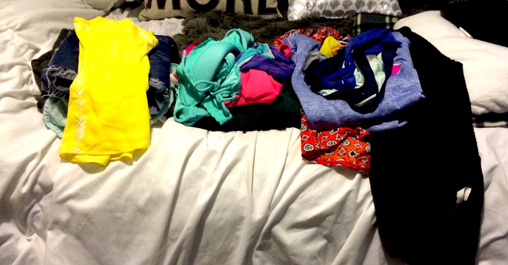 This is a picture of laundry folded and laid out on a bed.